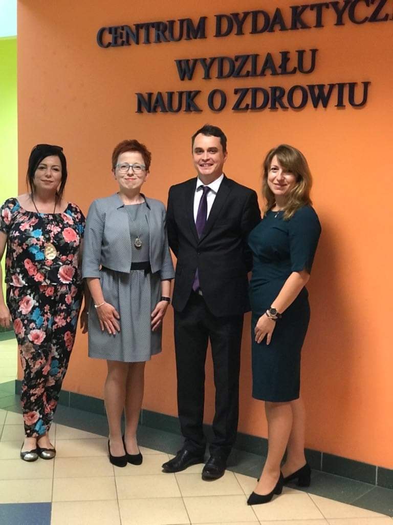 Cztery osoby stoją przed ścianą z napisem "CENTRUM DYDAKTYCZNE WYDZIAŁU NAUK O ZDROWIU".