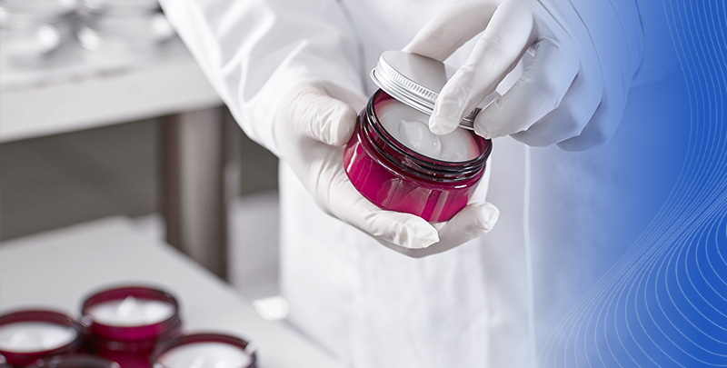 Kierunek Kosmetologia obejmuje chemię kosmetyczną, recepturę kosmetyków, analizę ich składów oraz zagadnienia związane z doborem preparatów kosmetycznych. Osoba w rękawiczkach otwiera pojemnik z kremem w laboratorium