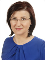 Kobieta w okularach, w niebieskiej bluzce, z krótkimi włosami.