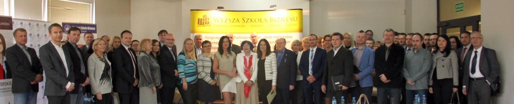 Grupa osób pozująca razem w budynku uczelni.