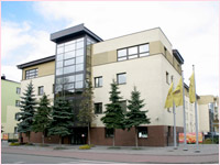 Budynek z&nbsp;dużymi oknami, otoczony drzewami, z&nbsp;dwoma flagami przed wejściem.