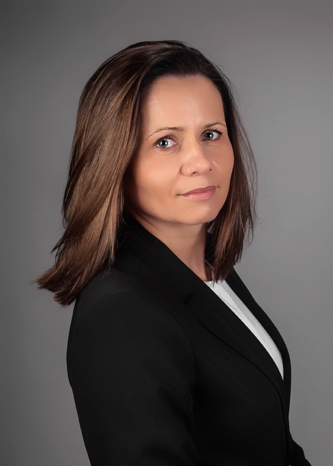 Portret kobiety z długimi, prostymi włosami, ubraną w czarną marynarkę.