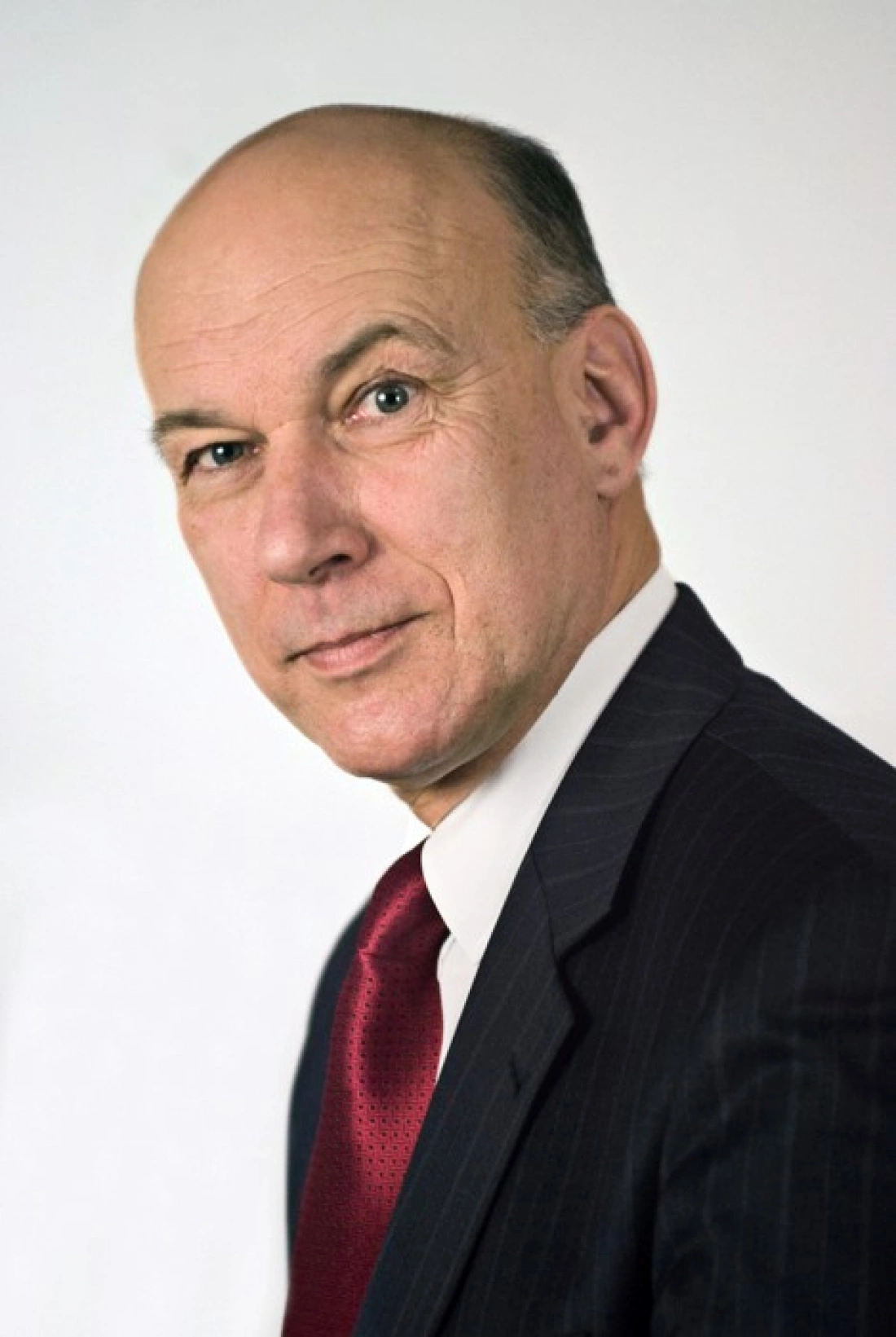 Mężczyzna w garniturze z krawatem, patrzący w stronę kamery.