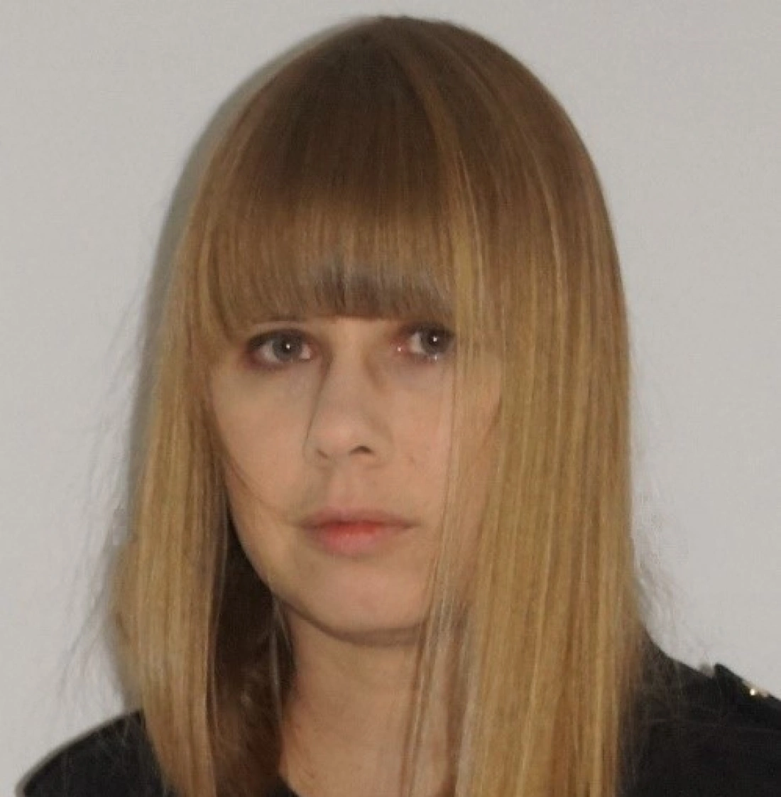 Kobieta o długich, prostych włosach w jasnym kolorze, z grzywką, patrząca w obiektyw.