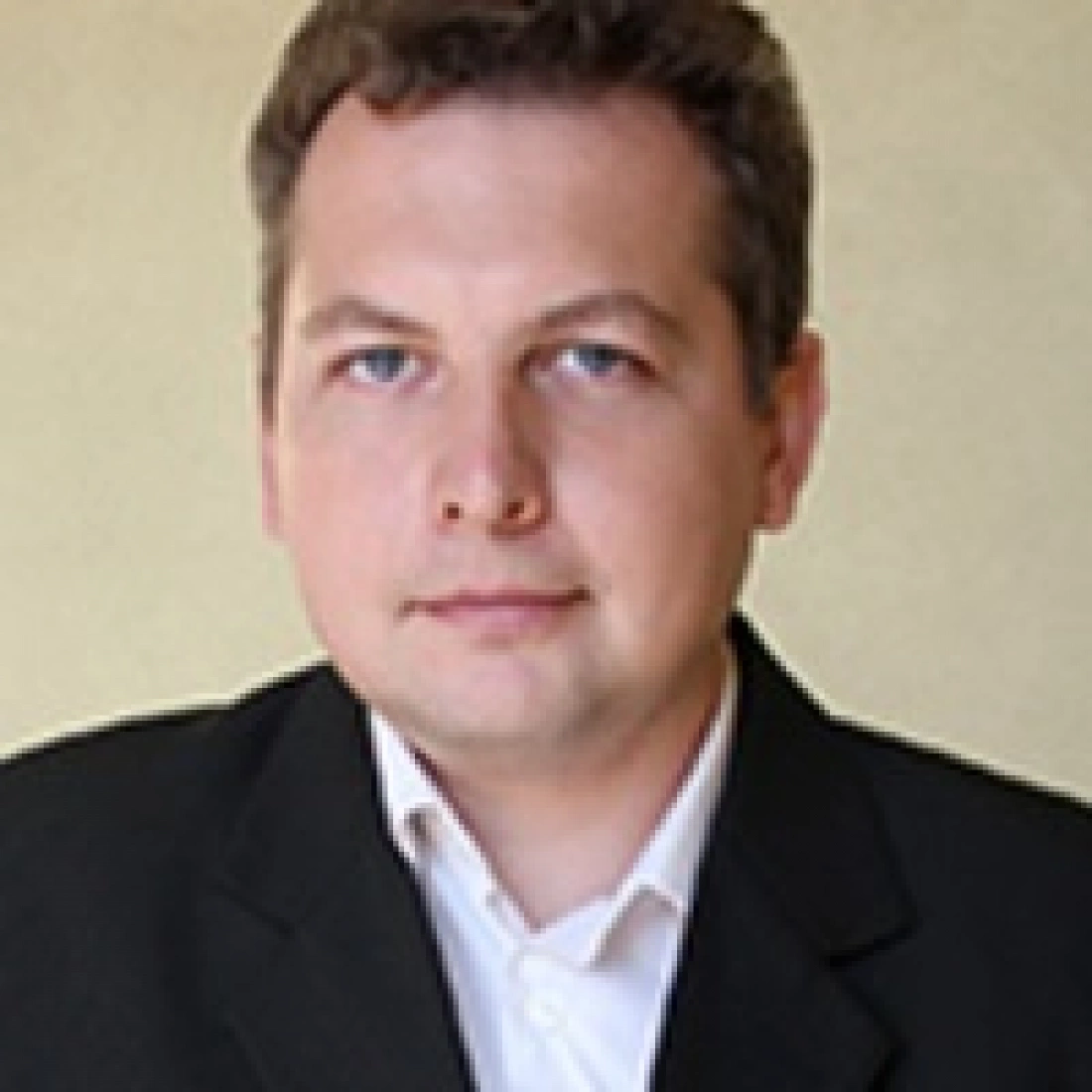 Mężczyzna w eleganckim stroju, patrzący w kamerę.