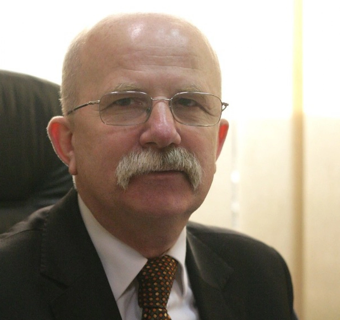 Mężczyzna z okularami i wąsami, ubrany w garnitur.