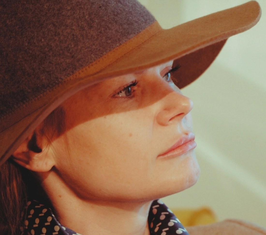 Kobieta w kapeluszu z szerokim rondem, patrząca w bok.