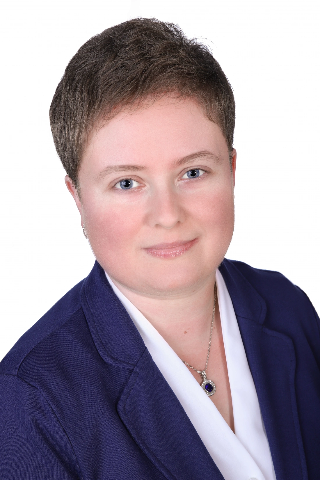 Portret kobiety w niebieskiej marynarce, uśmiechającej się w kierunku obiektywu.