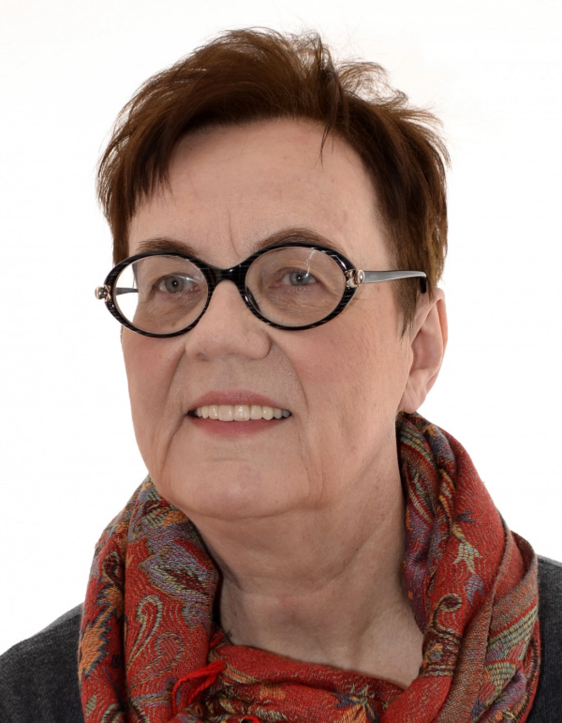 Portret starszej kobiety w okularach i kolorowym szalu.