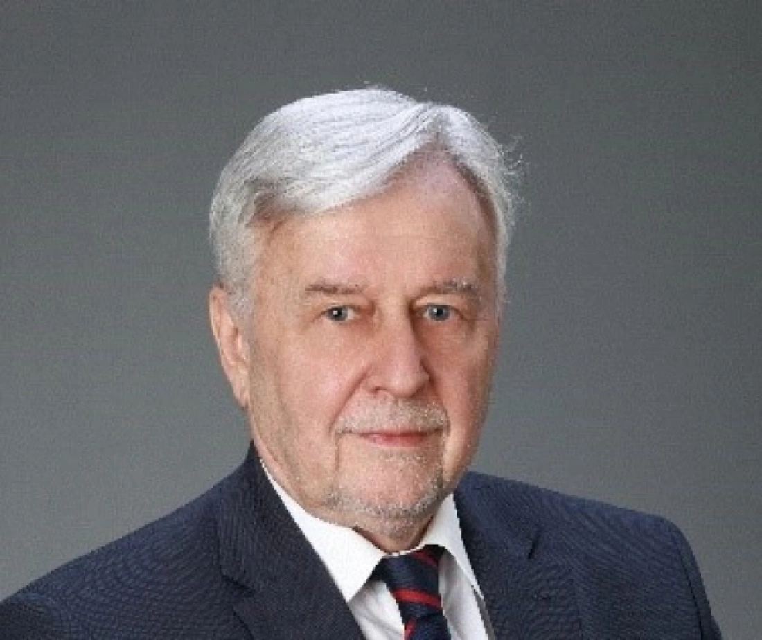 Mężczyzna w średnim wieku z siwymi włosami, uśmiechający się, ubrany w elegancki garnitur.