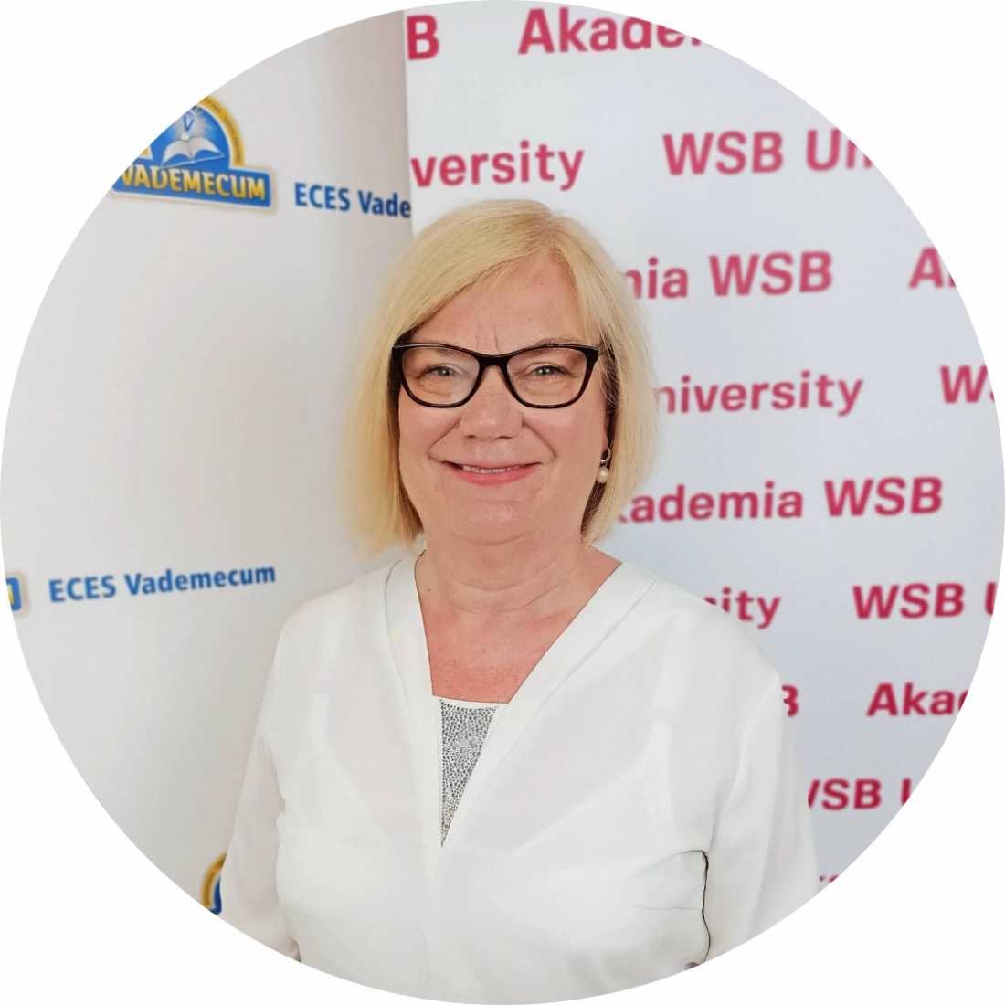 Kobieta w okularach stoi na tle banerów Akademii WSB.
