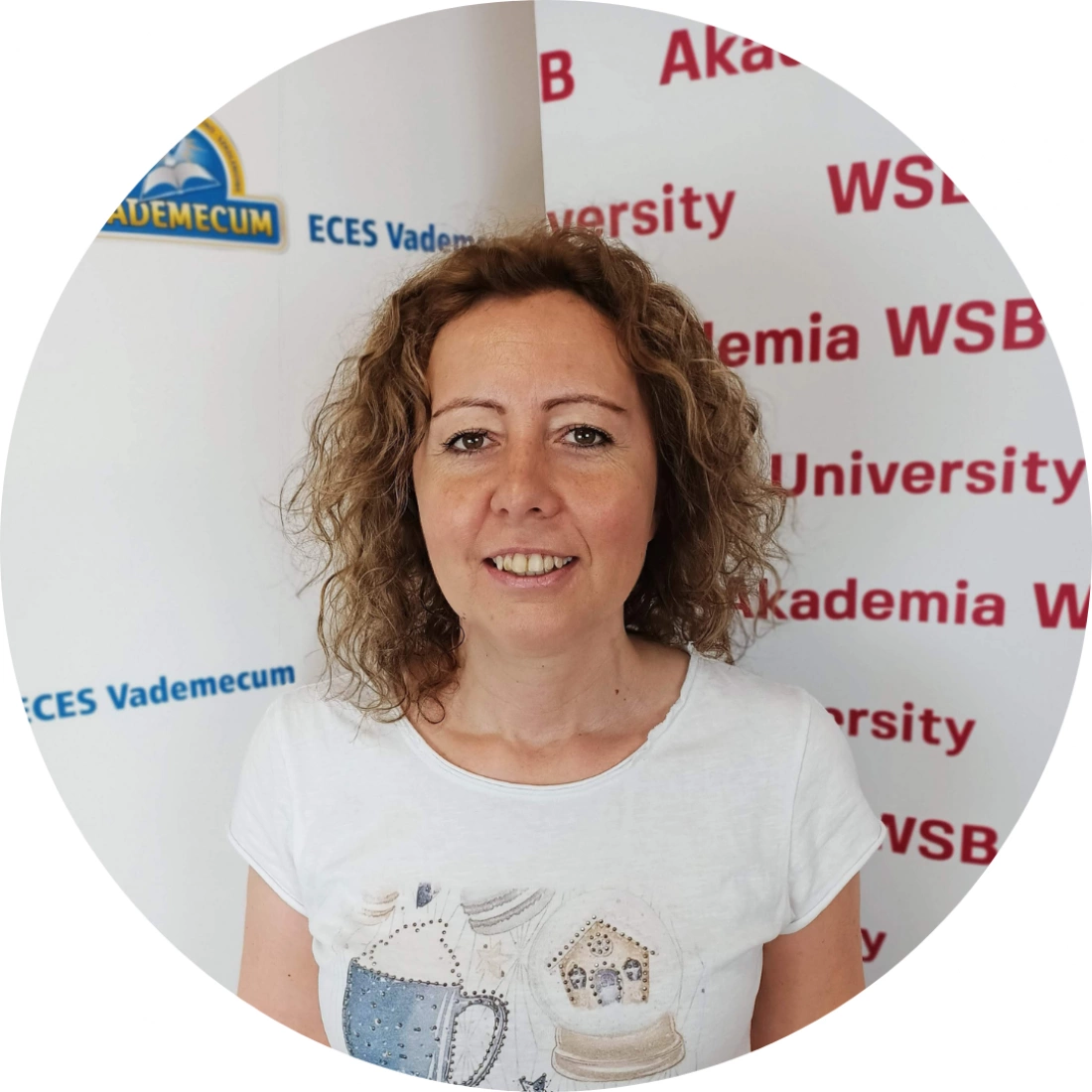 Kobieta z kręconymi włosami stoi przed tłem z napisami "Akademia WSB".