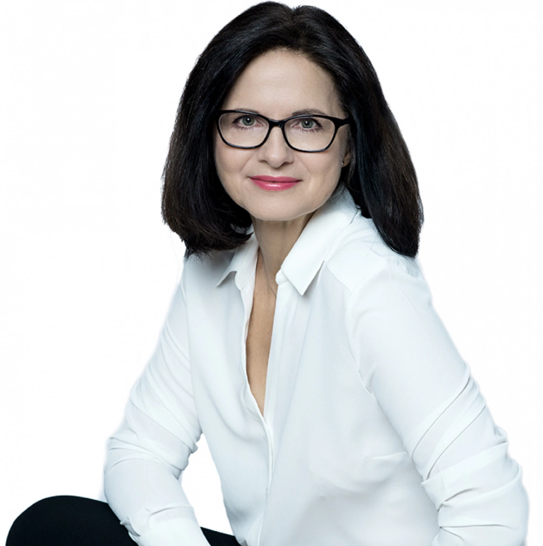 Kobieta w białej koszuli, z okularami, uśmiechająca się na zdjęciu.