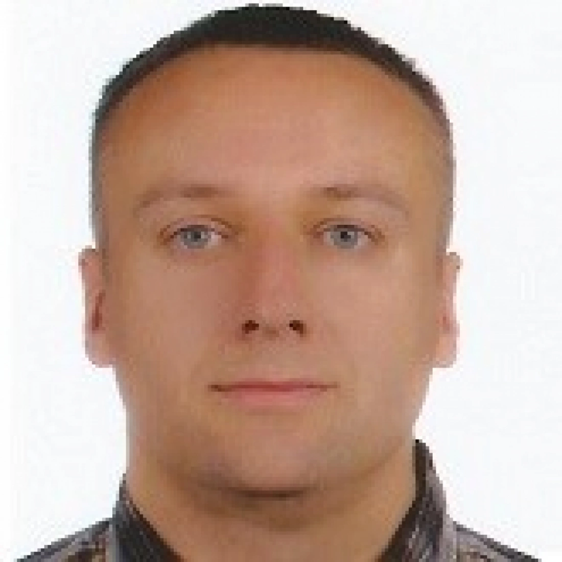 Portret mężczyzny z jasnymi oczami i krótkimi włosami.