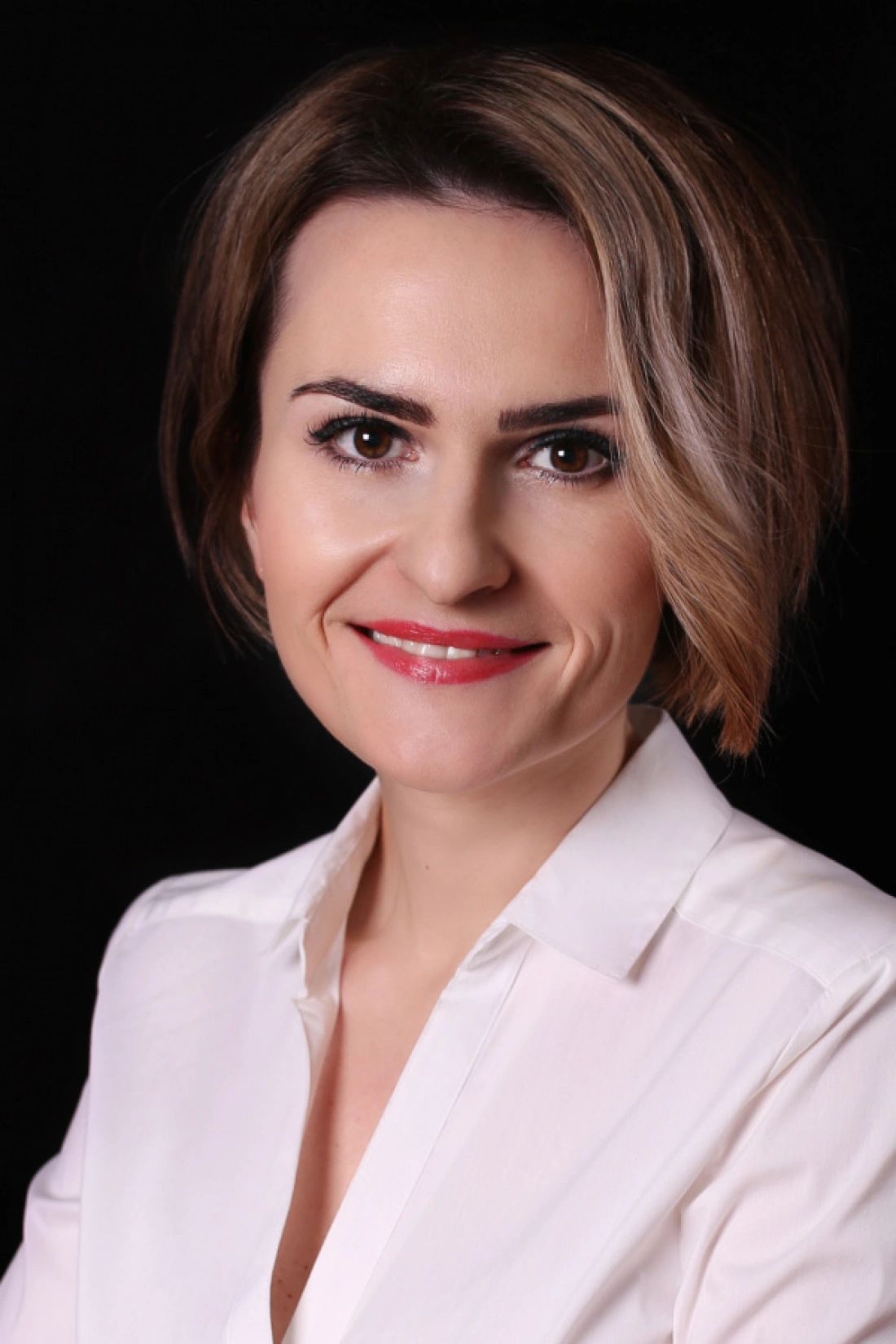 Portret kobiety w białej koszuli na czarnym tle.