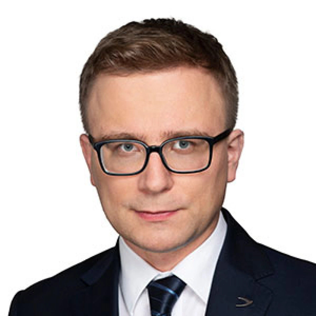 Mężczyzna w okularach, ubrany w garnitur, z poważnym wyrazem twarzy.