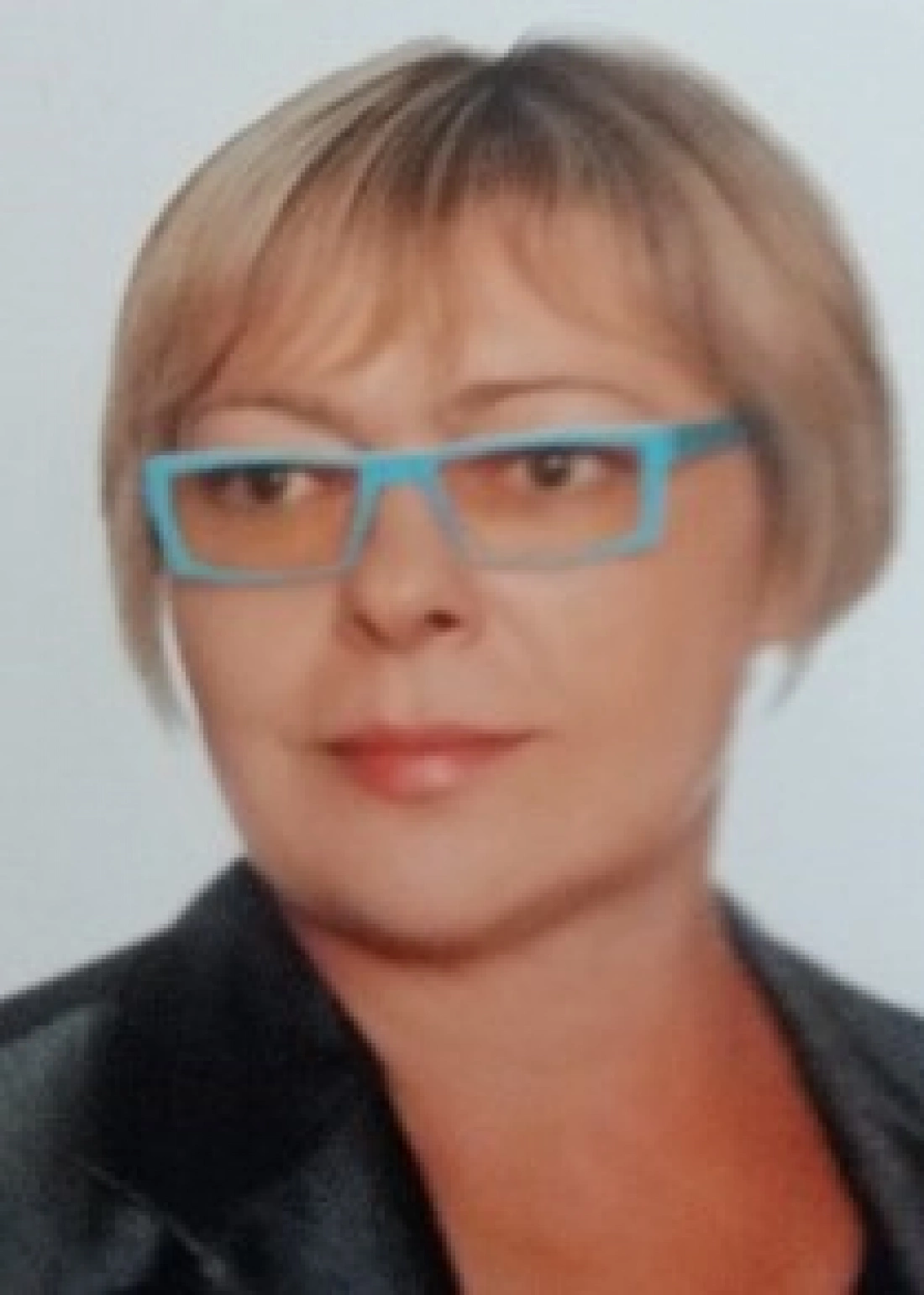 Kobieta z krótkimi włosami w okularach, uśmiechająca się delikatnie.