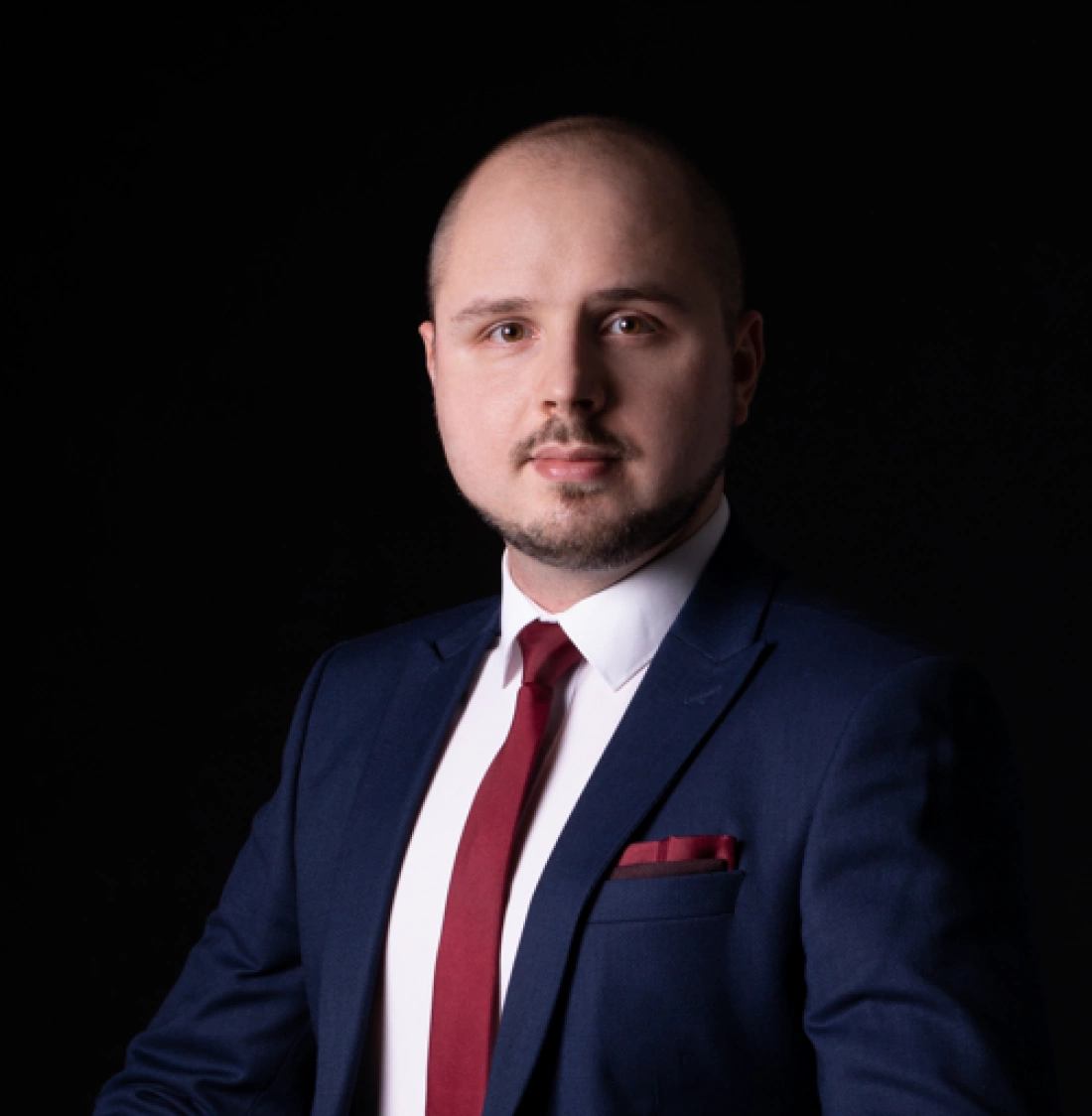 Mężczyzna w eleganckim garniturze na ciemnym tle.