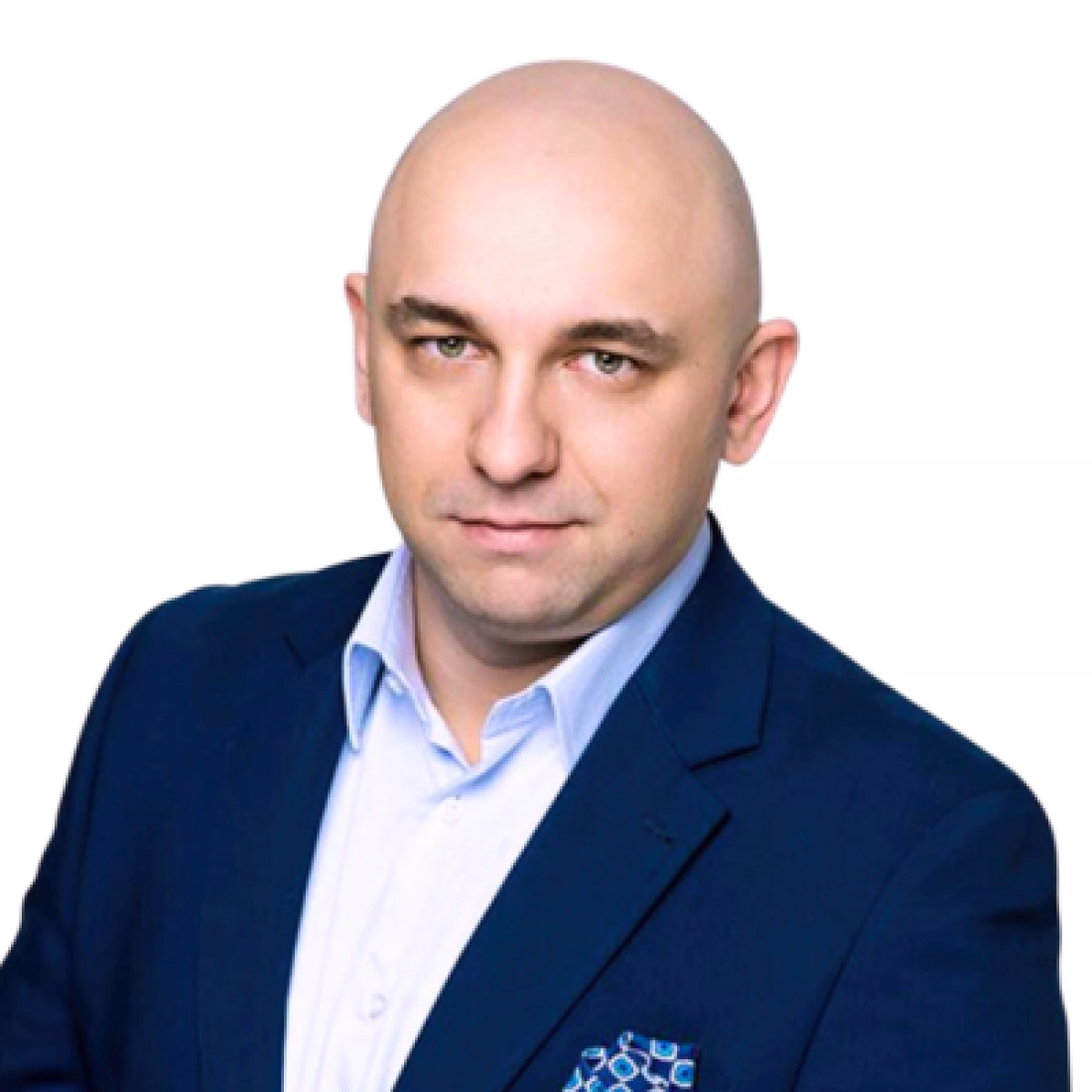 Mężczyzna w eleganckim garniturze, z gładko ogoloną głową, patrzy prosto w obiektyw.