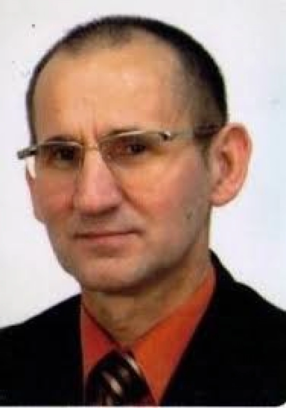 Mężczyzna w okularach, ubrany w garnitur i krawat.