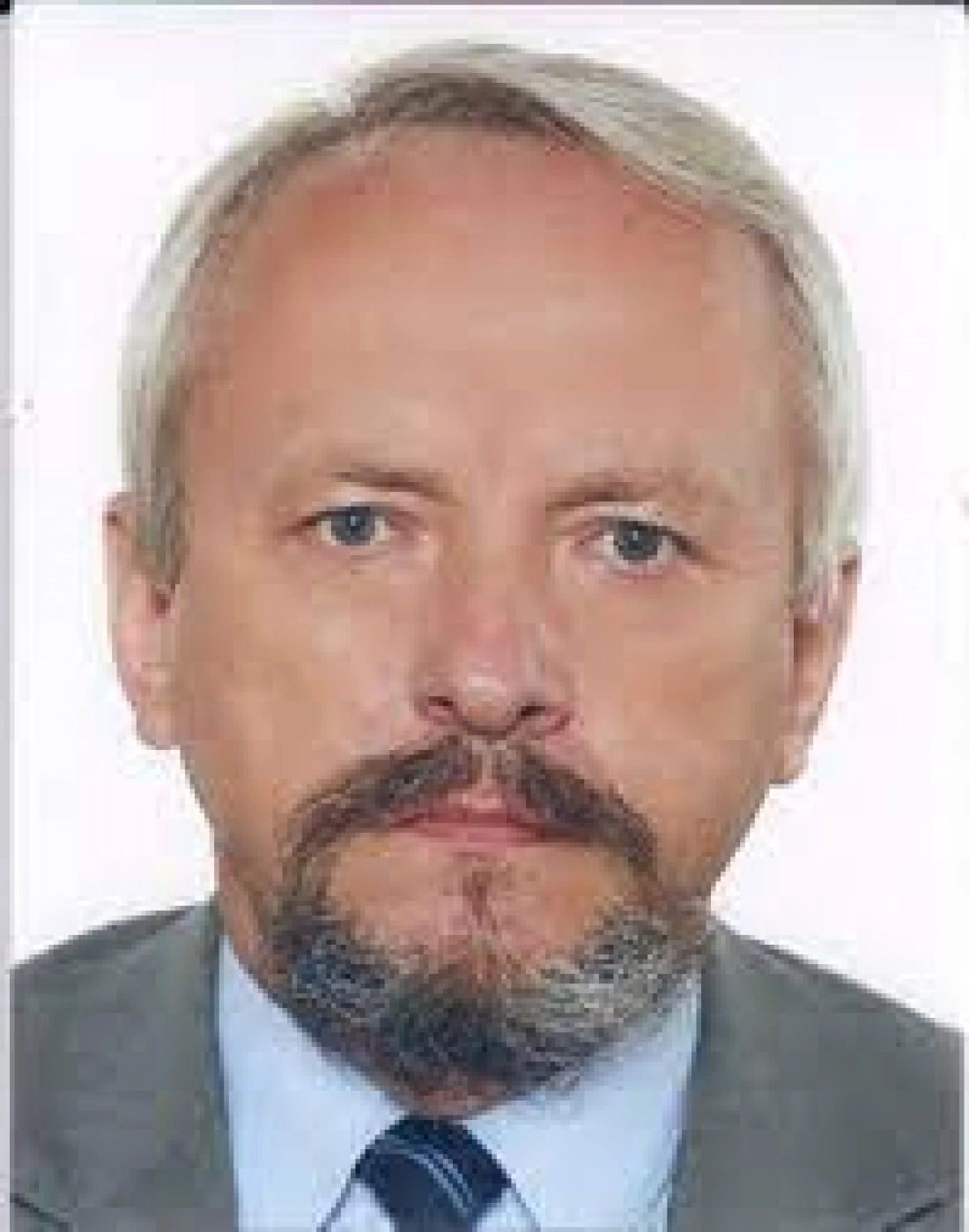 Mężczyzna z siwymi włosami i brodą, ubrany w garnitur.