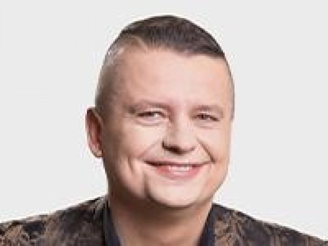 Uśmiechnięty mężczyzna z krótkimi włosami w stylowej koszuli.