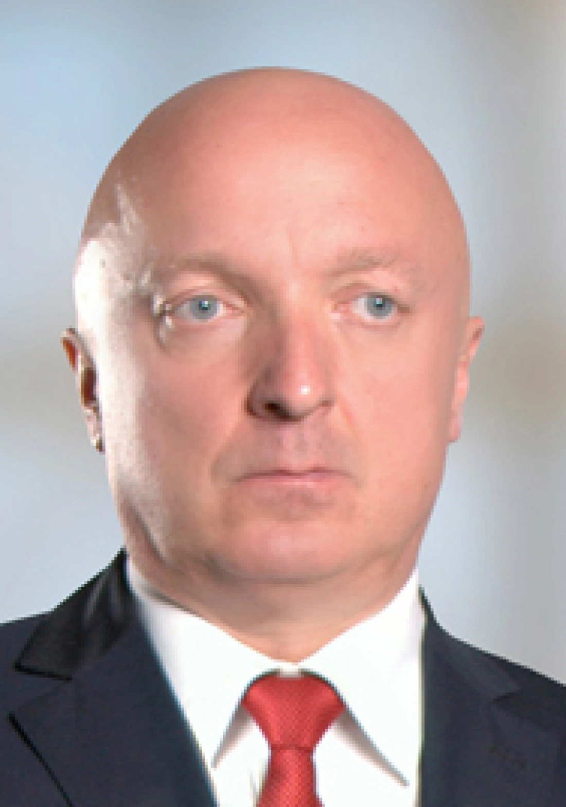 Poważny mężczyzna w garniturze z czerwonym krawatem.