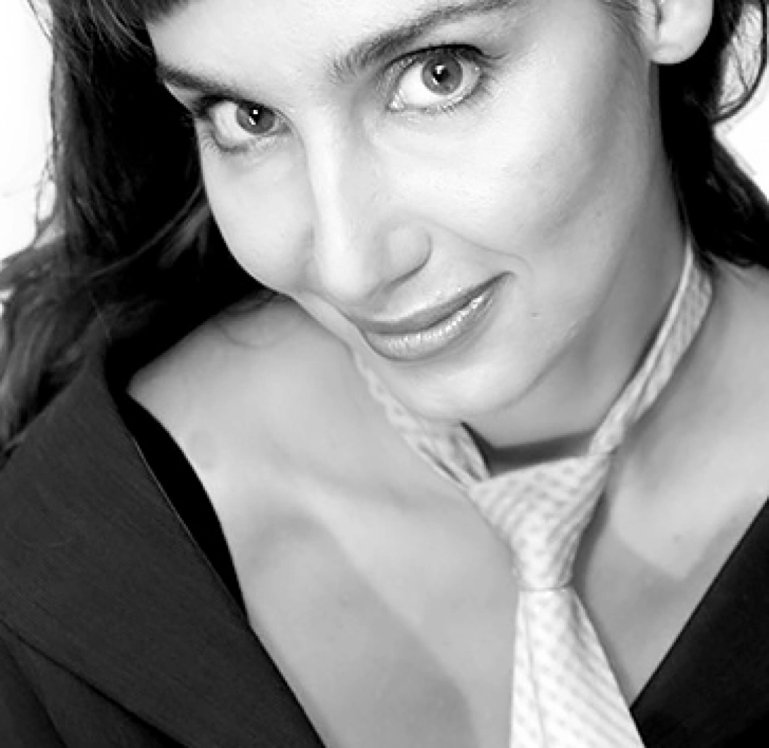 Portret uśmiechającej się kobiety w eleganckim stroju, z kokardą na szyi.