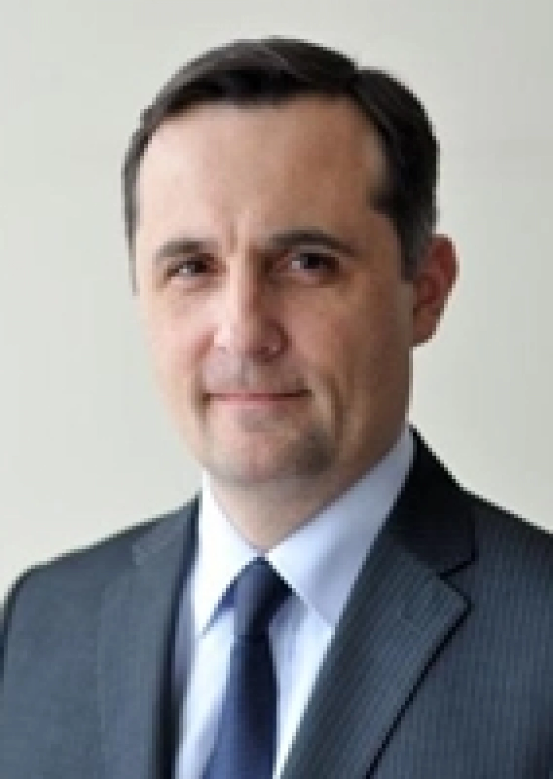 Mężczyzna w garniturze z poważnym wyrazem twarzy.