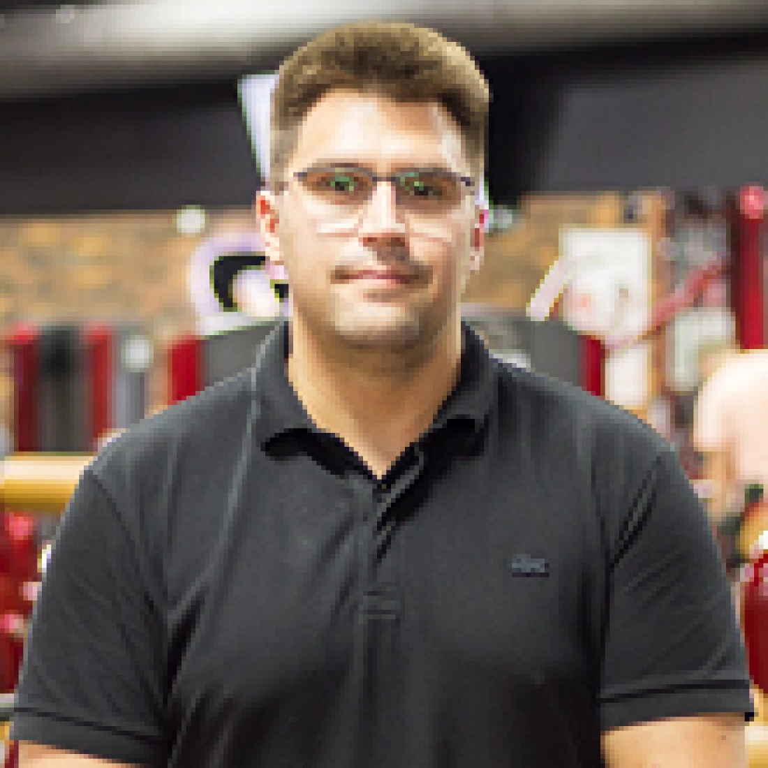 Mężczyzna w czarnej koszulce, stojący w siłowni.