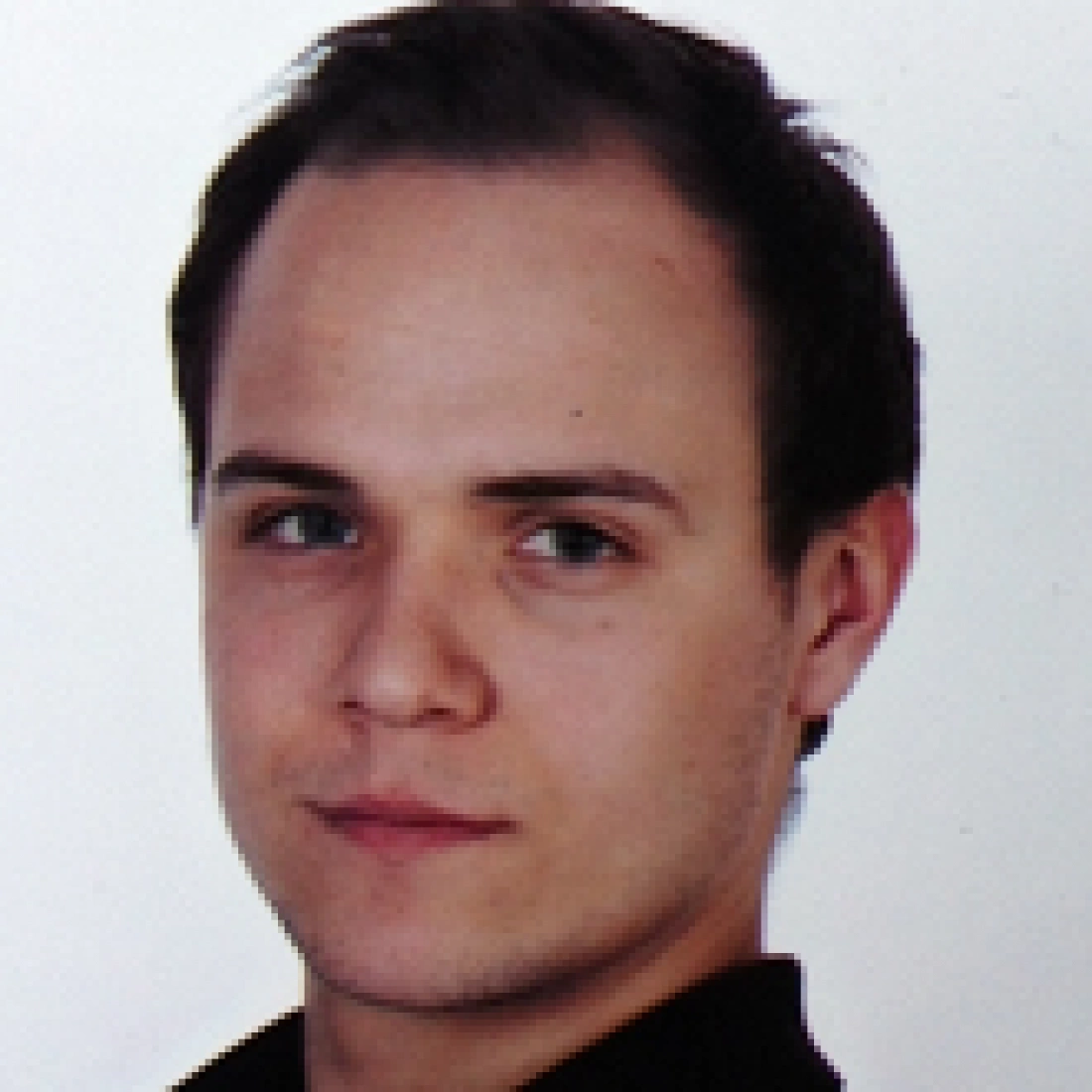 Mężczyzna z krótkimi włosami, prezentujący poważny wyraz twarzy.