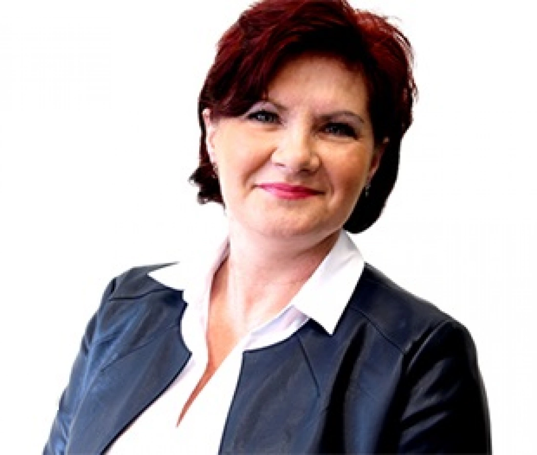 Kobieta o krótkich, ciemnych włosach ubrana w elegancki żakiet.