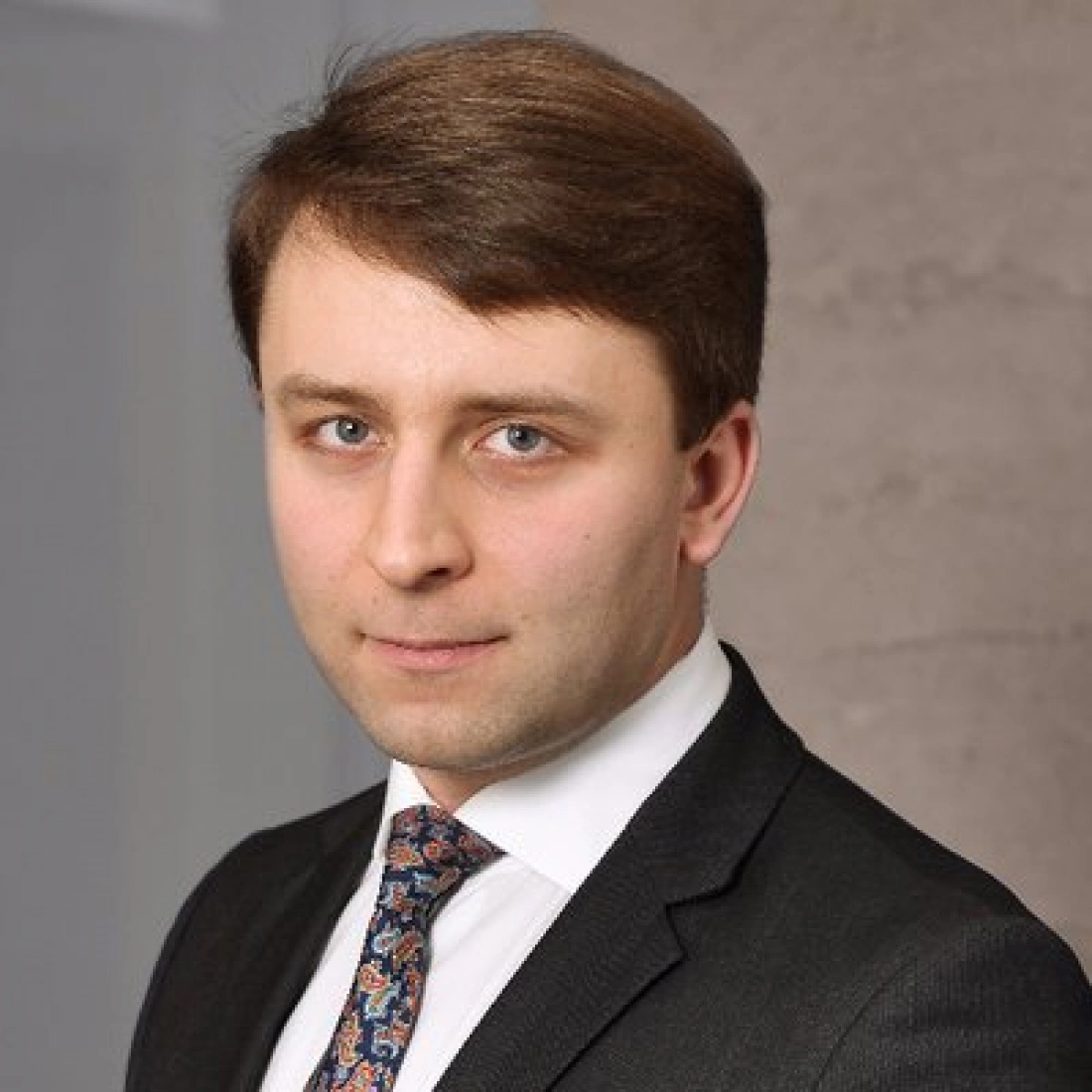 Mężczyzna w garniturze z krawatem, patrzący prosto w kamerę.