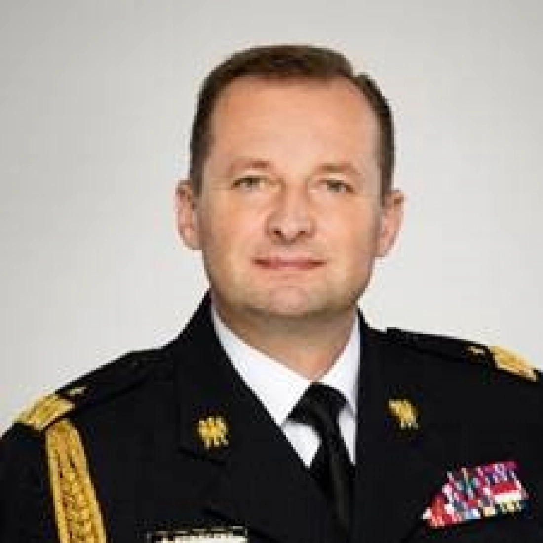 Mężczyzna w mundurze wojskowym, z odznaczeniami, uśmiechający się do kamery.
