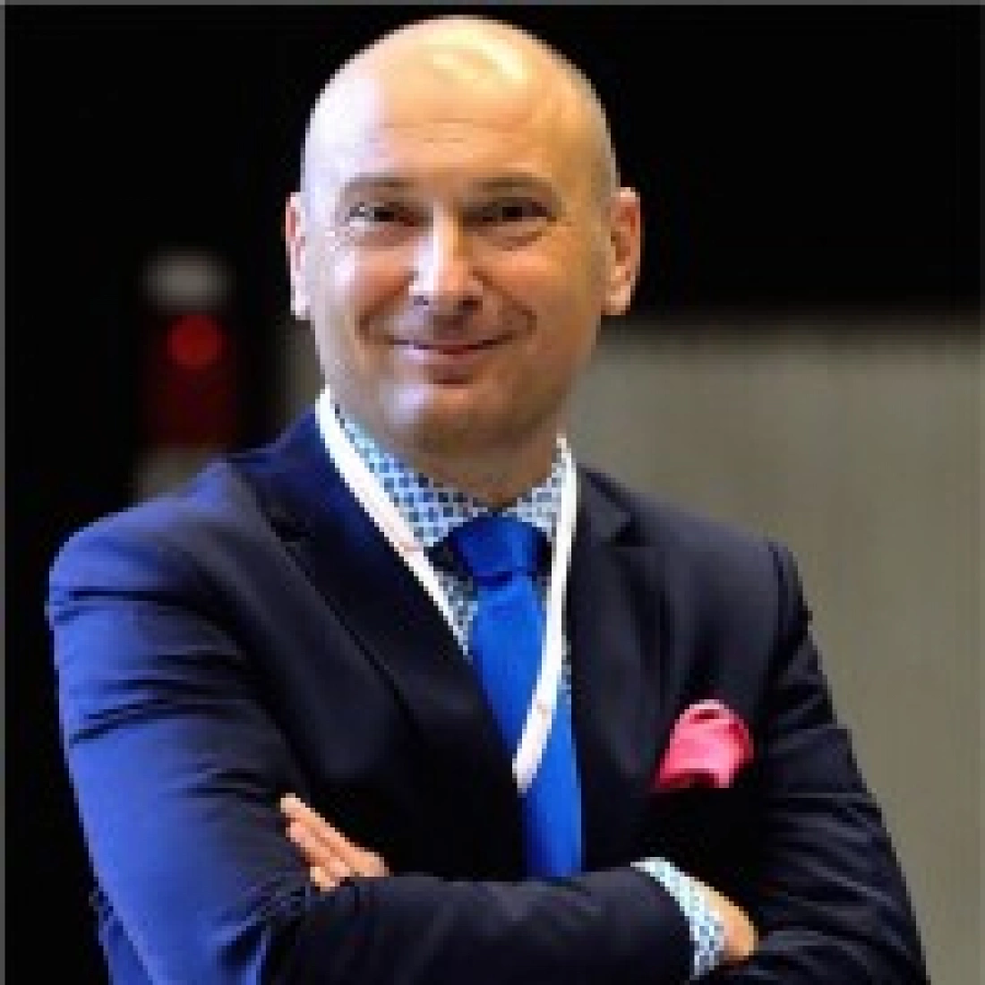Uśmiechnięty mężczyzna w eleganckim garniturze z niebieskim krawatem.