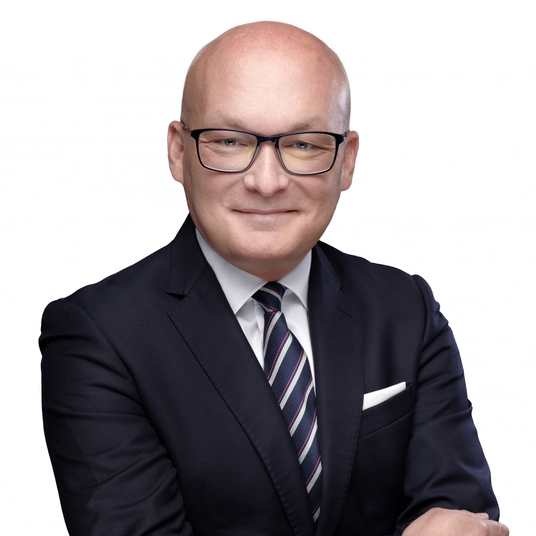 Mężczyzna w garniturze z okularami, uśmiechający się na białym tle.