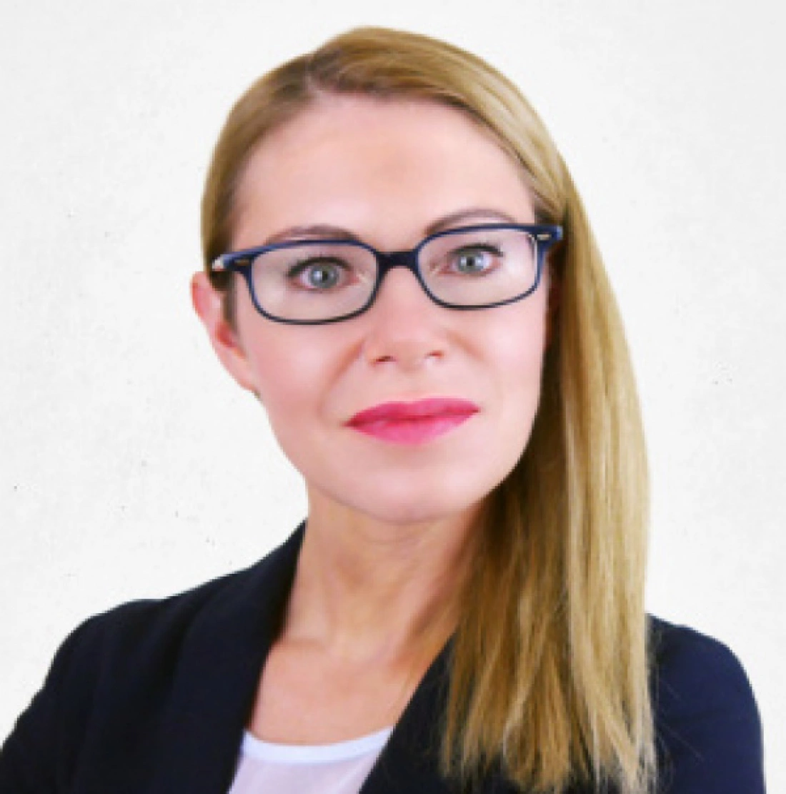 Kobieta w okularach, z długimi prostymi włosami, uśmiechająca się pewnie w eleganckim stroju.