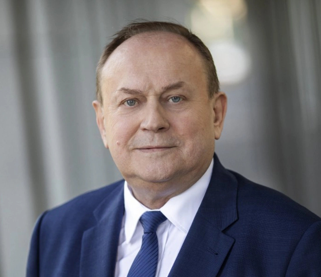 Mężczyzna w garniturze, uśmiechający się do kamery.