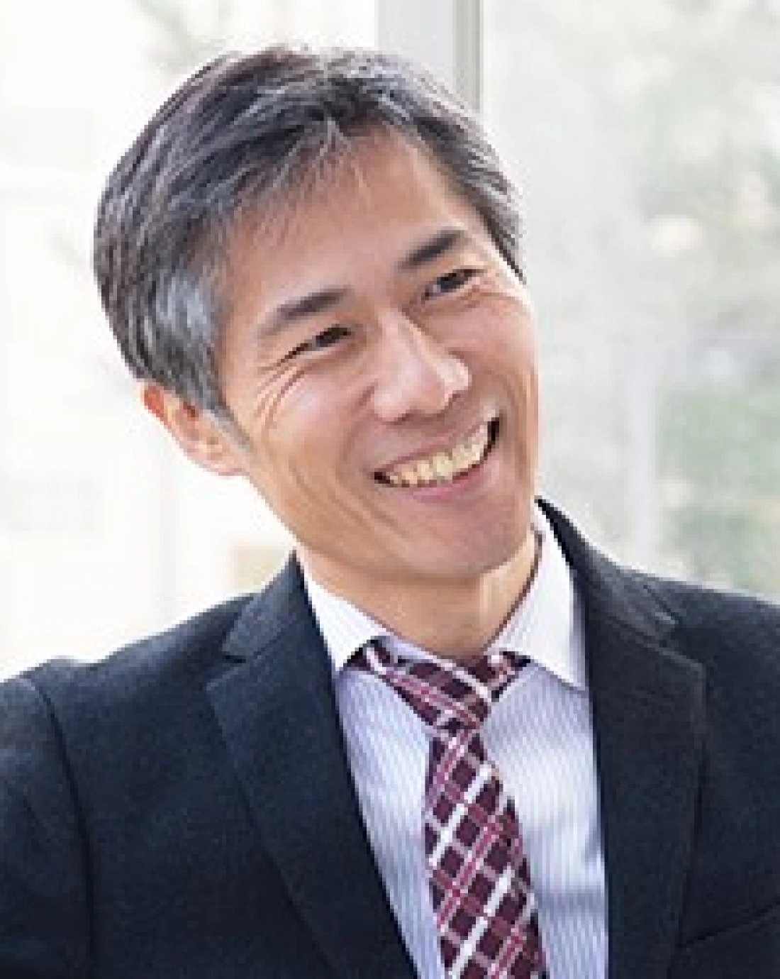 Uśmiechający się mężczyzna w garniturze, wyglądający na zadowolonego.