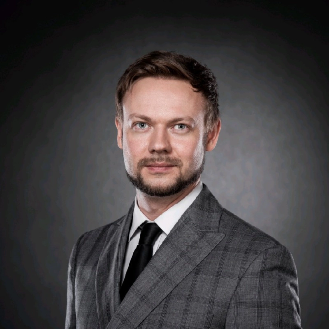 Mężczyzna w eleganckim garniturze na ciemnym tle.