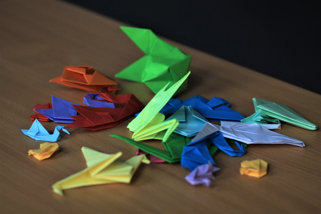 Kawałek stołu z kolorowymi origami w r&oacute;żnych kształtach.