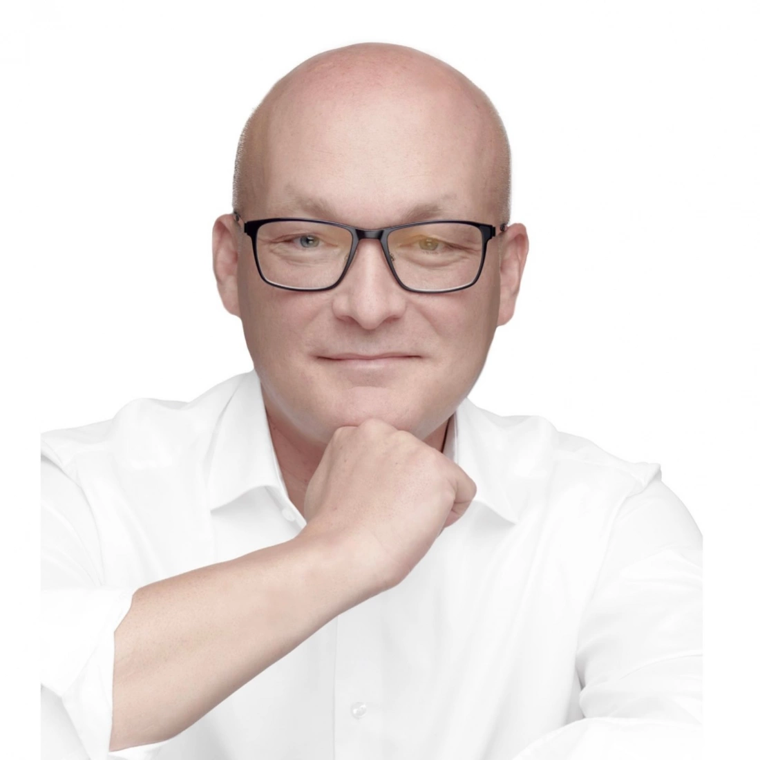 Mężczyzna w białej koszuli, z okularami, z poważnym uśmiechem i ręką przy brodzie.