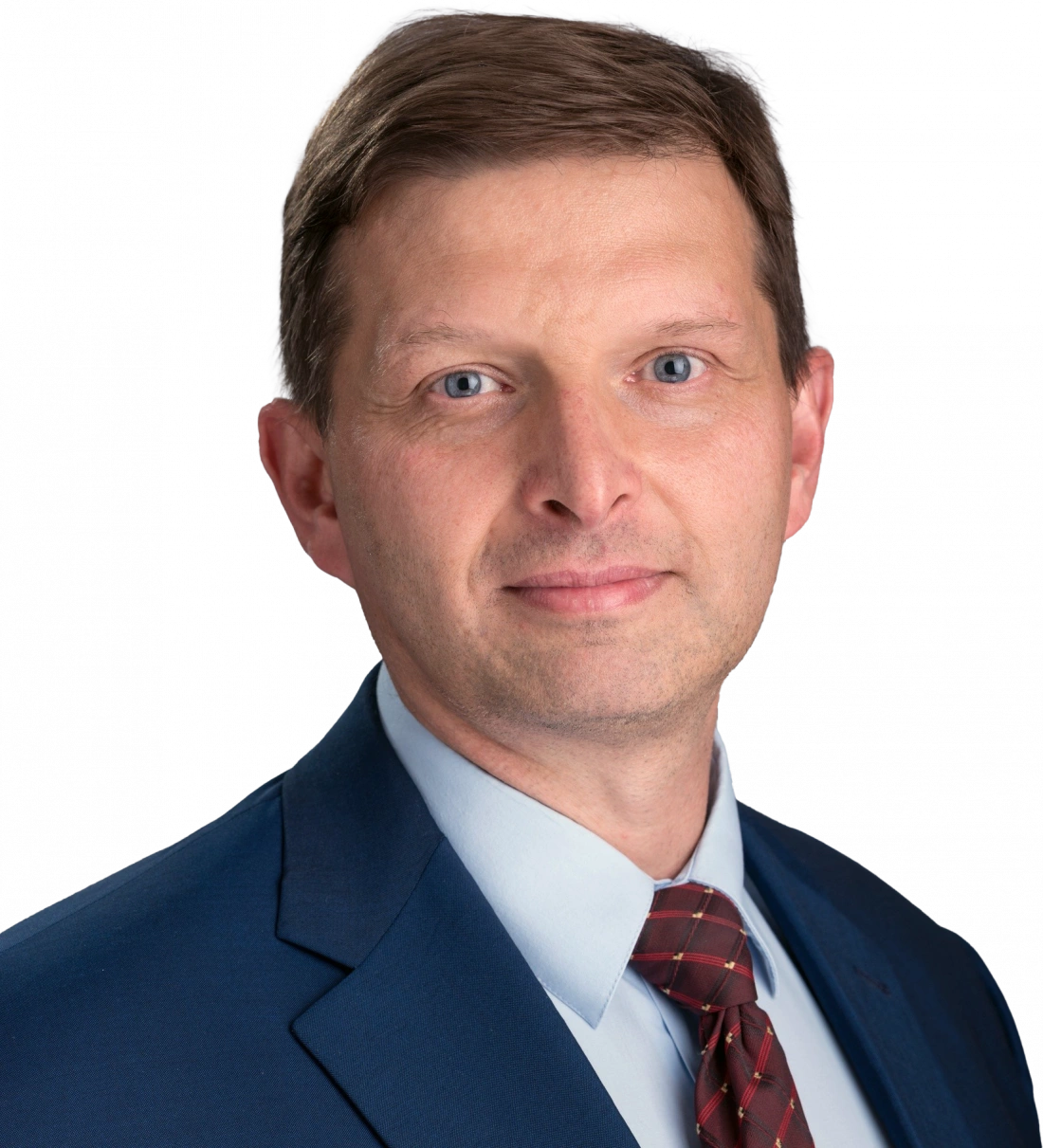 Mężczyzna w garniturze, z uśmiechem i niebieskimi oczami, na neutralnym tle.