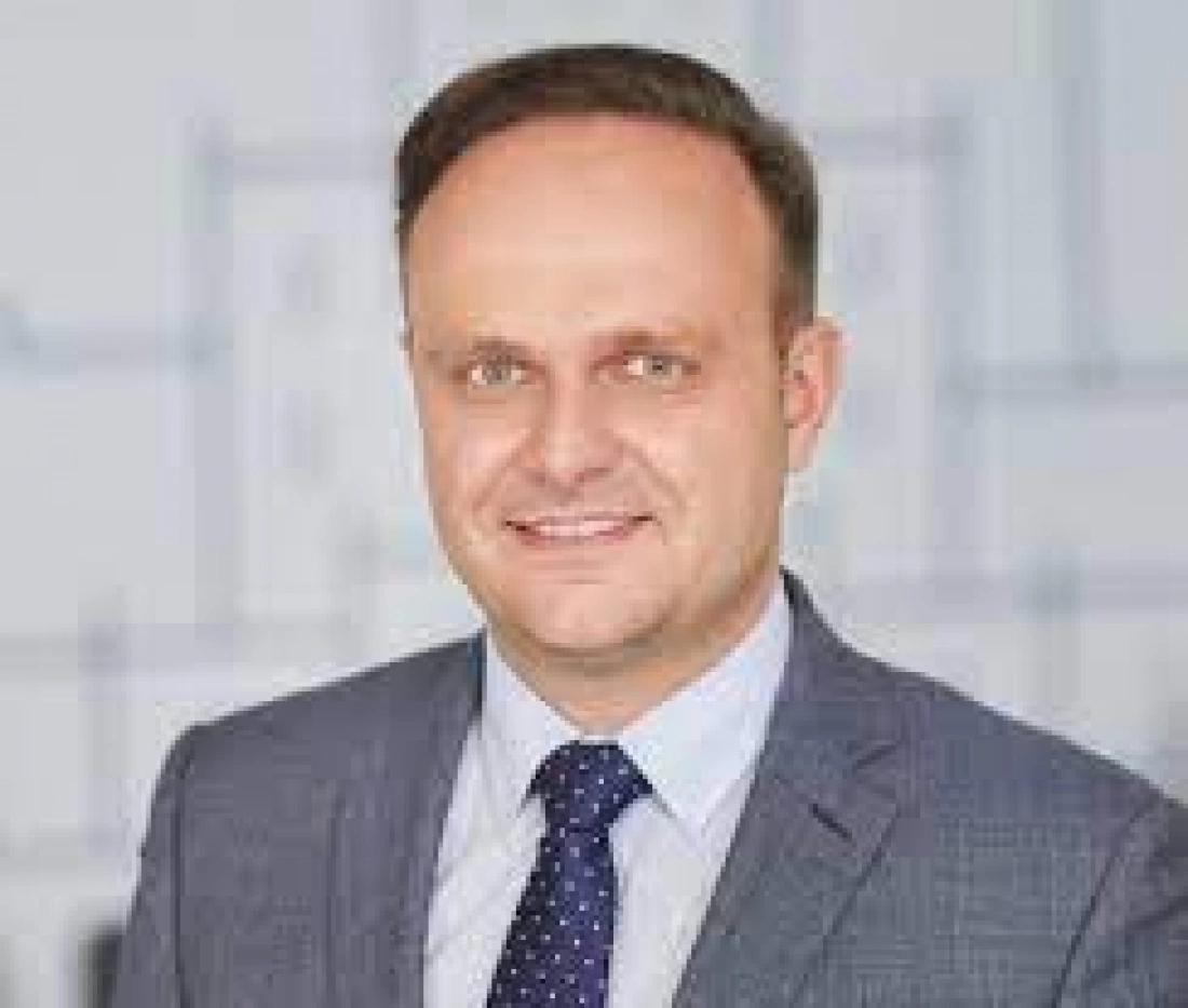 Mężczyzna w garniturze z eleganckim uśmiechem.