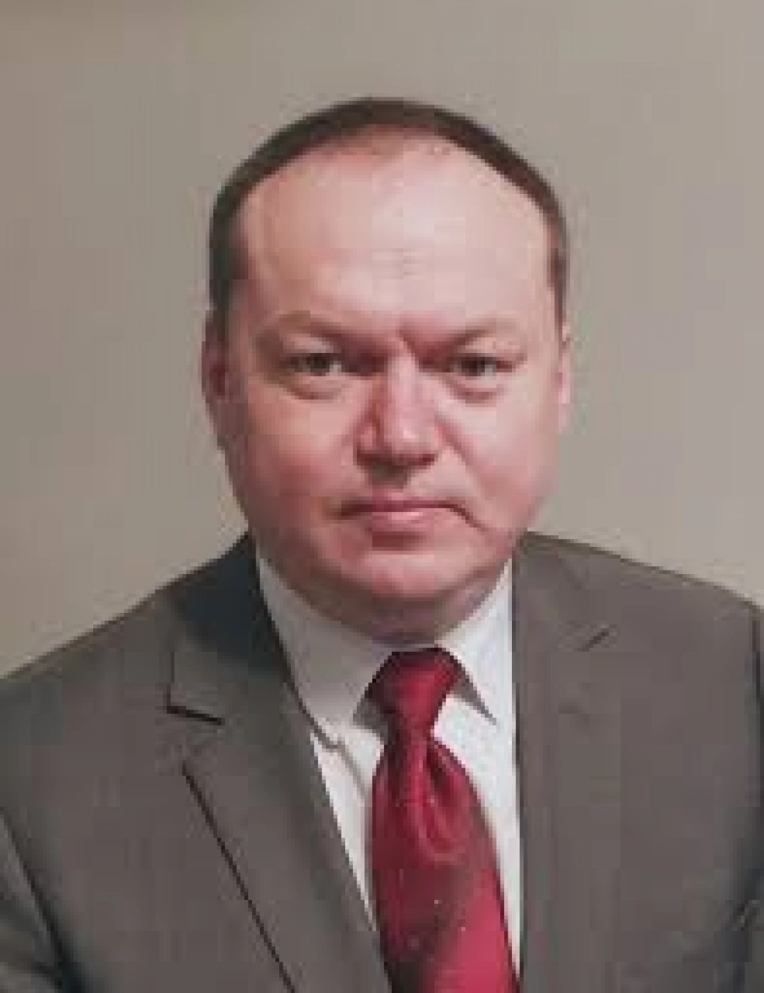 Mężczyzna w garniturze z krawatem, patrzący w stronę kamery.