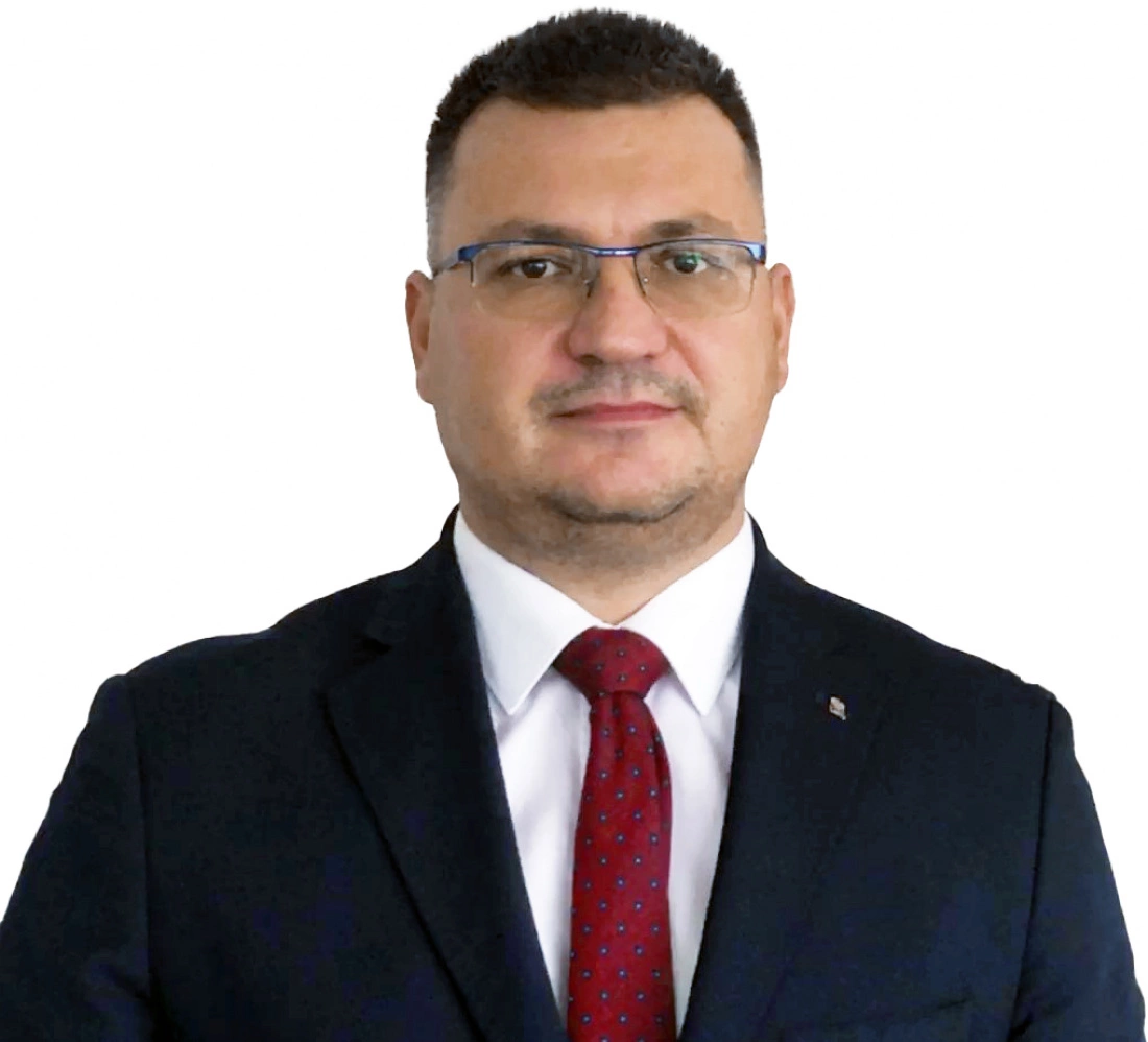 Mężczyzna w garniturze z krawatem, pozujący na białym tle.