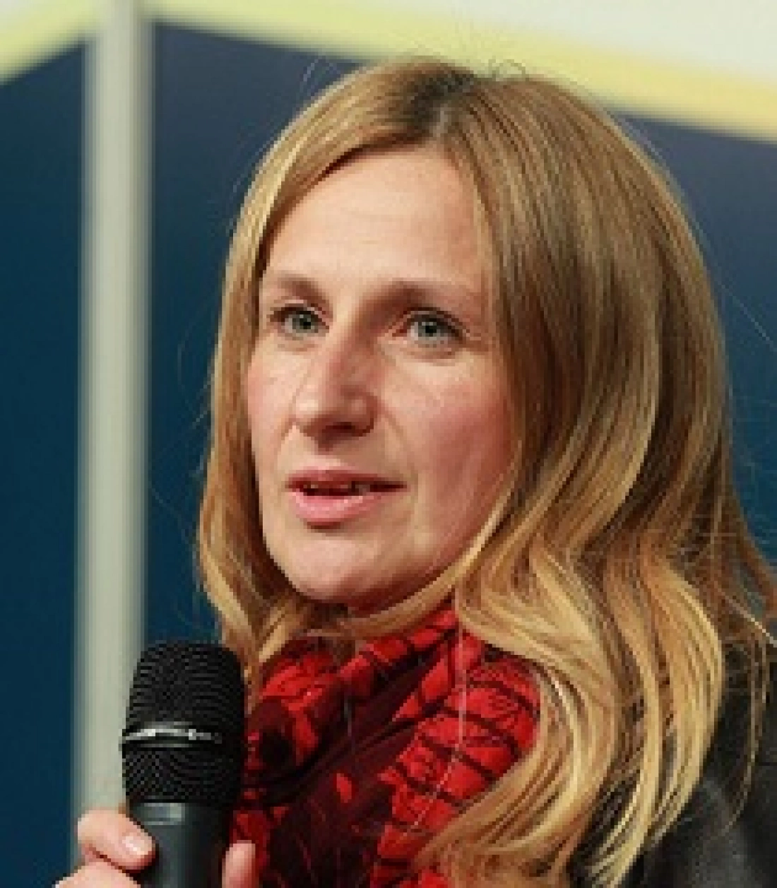 Kobieta z mikrofonem, uśmiechająca się i rozmawiająca.