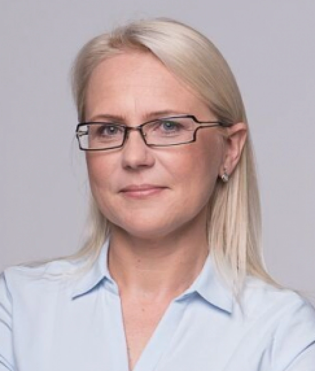 Kobieta z długimi blond włosami i okularami, uśmiechająca się pewnie.