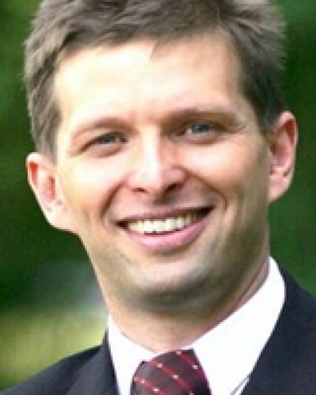 Mężczyzna w garniturze z uśmiechem na twarzy.