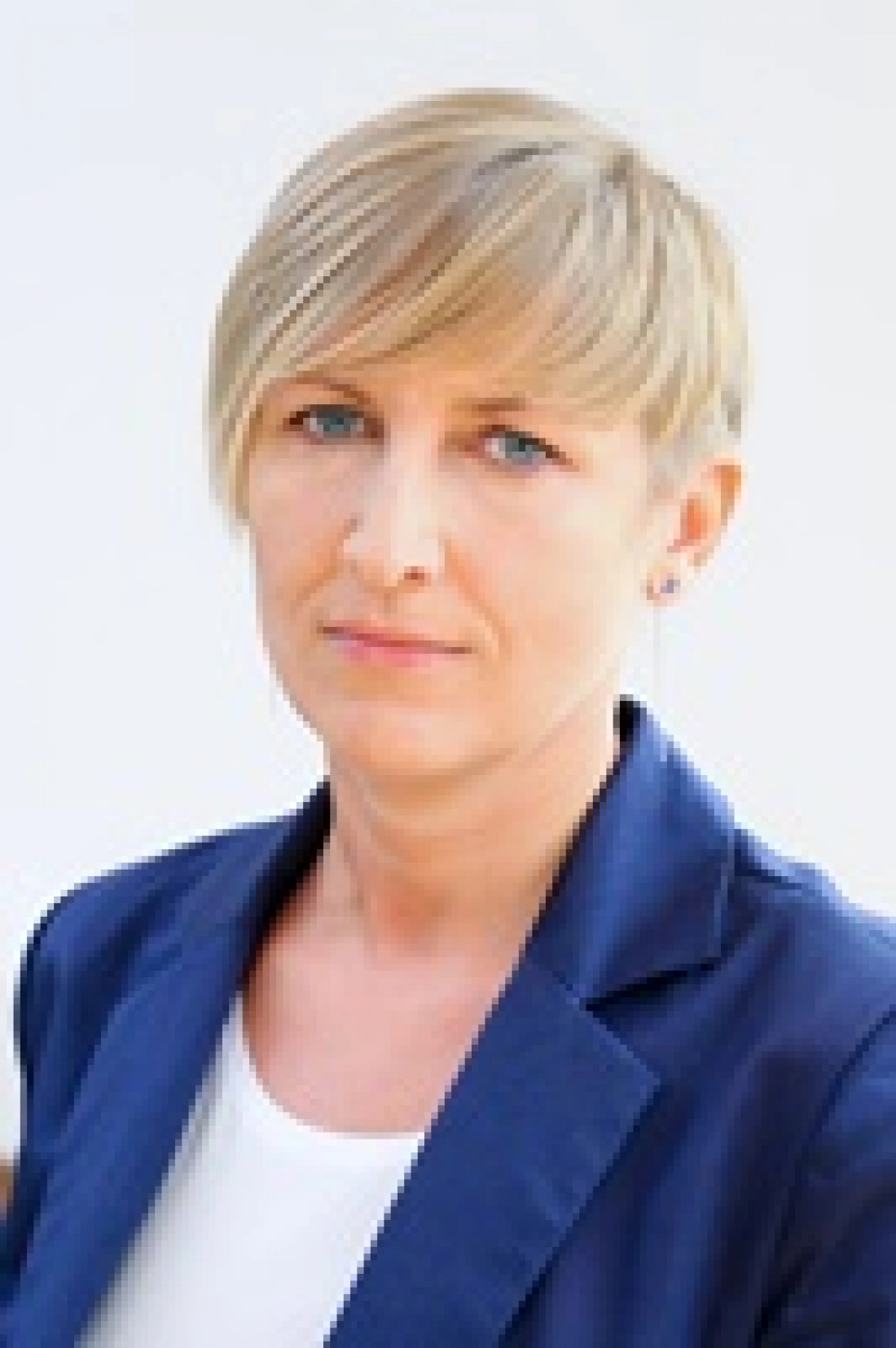 Kobieta w eleganckim stroju z krótkimi włosami, patrząca prosto w kamerę.